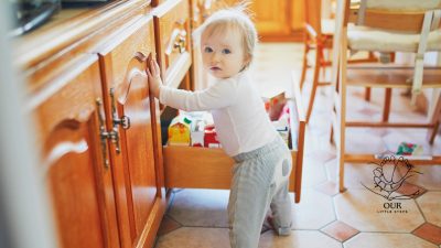 Baby crawling on a soft carpet in a babyproofed living room, surrounded by safety gates and secured furniture.
