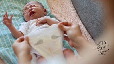 A baby lying on a changing mat with a parent applying diaper cream to soothe diaper rash.